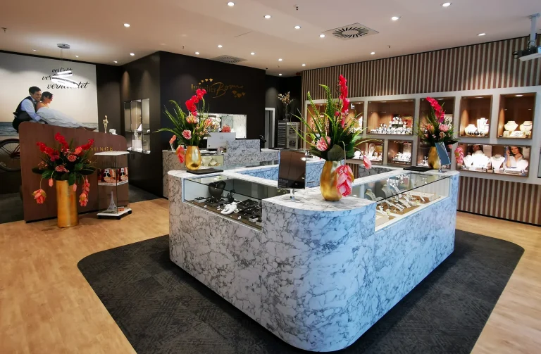 Blick ins Juwelier Born Fachgeschäft Schmuckgeschäft mit eleganter Theke, Blumenarrangements und Vitrinen voller Schmuckstücke.