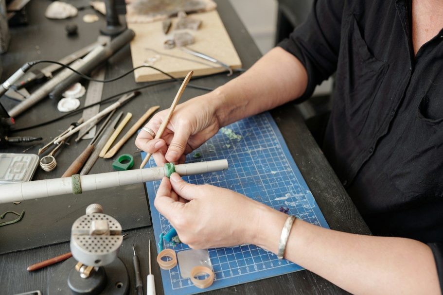 professionelle Reparatur- und Anpassungsarbeiten Eine Person arbeitet an einem handwerklichen Projekt mit Werkzeugen und Materialien auf einem Tisch.